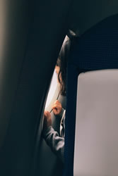 woman looking out window of plane